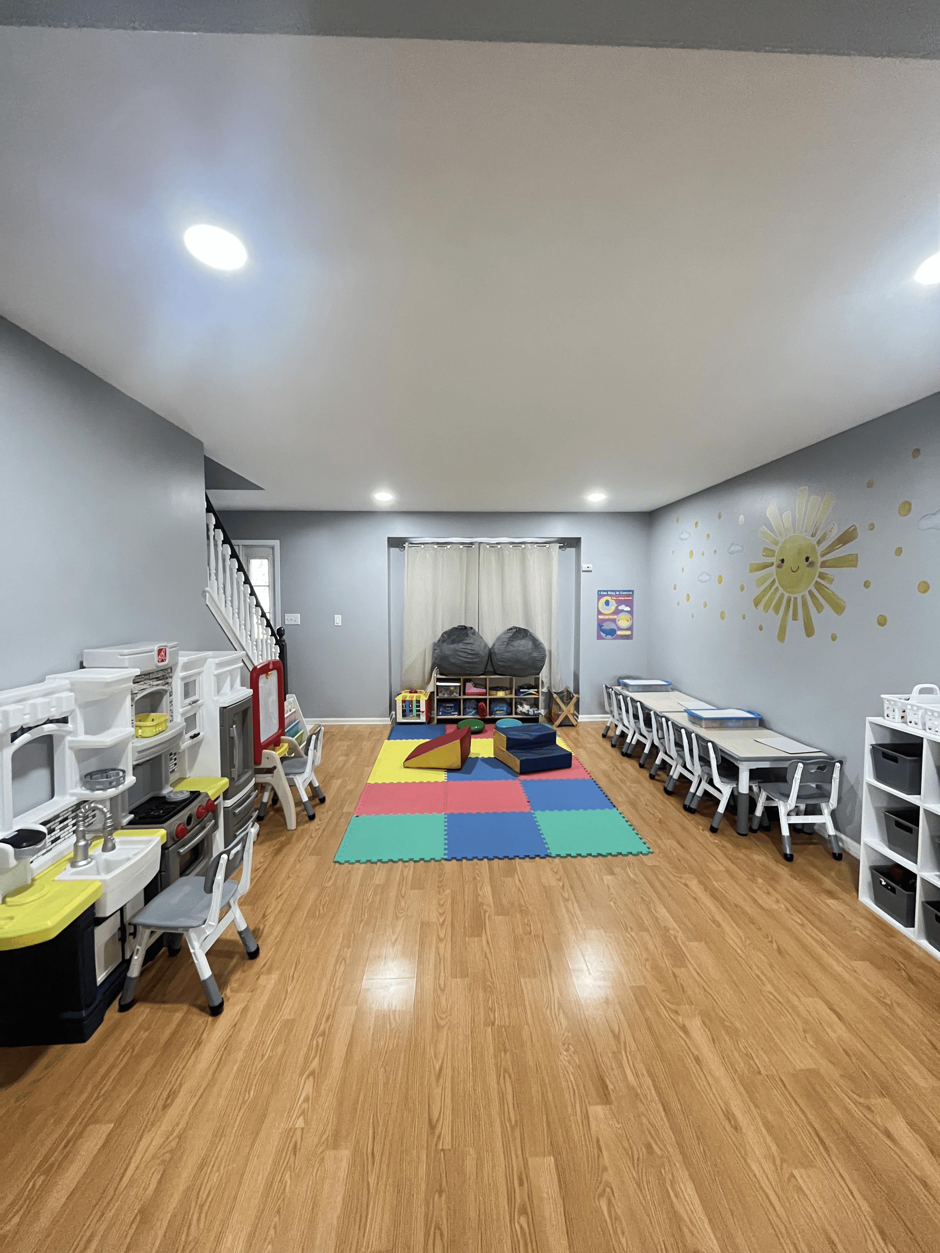 Wide view of the playroom with tables and colorful floor mats